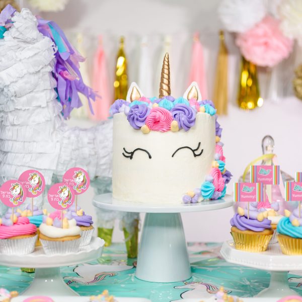 Little girl birthday party table with unicorn cake, cupcakes, and sugaer cookies.